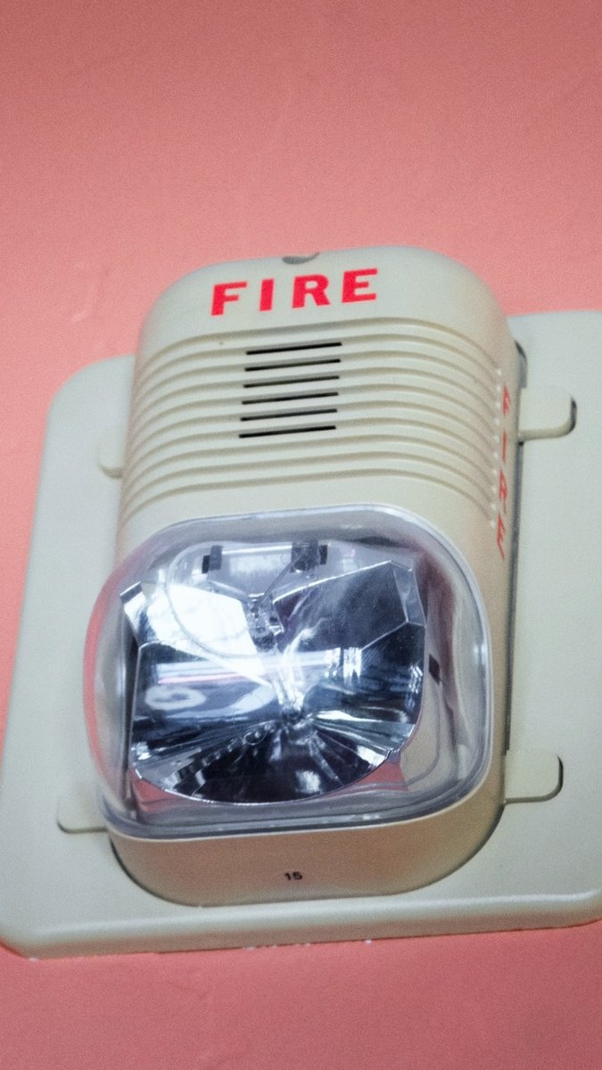 Wall-mounted fire alarm with visual strobe and audible alert